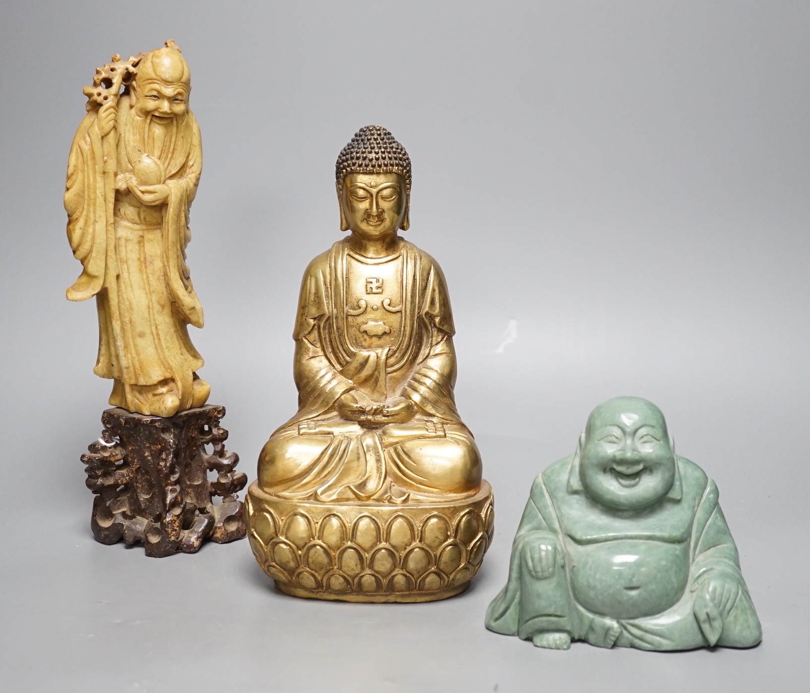 A Chinese greenstone Buddha, a soapstone carving of Shou Lao on carved hardwood stand, and a bronze figure of a seated Shaykamuni Buddha, tallest 29cm
